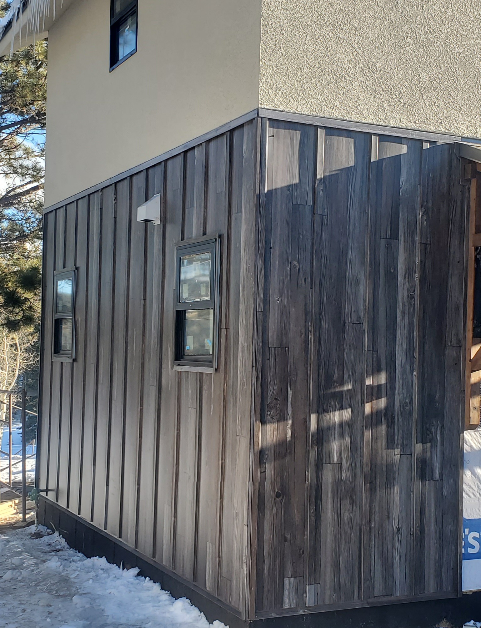 Wood-look board and batten style metal siding installed on a Colorado mountain home
